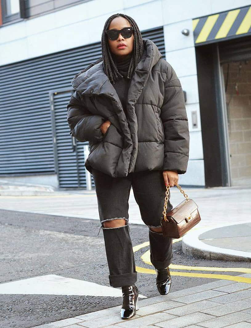 femme noire portant un manteau noir avec un jean déchiré et des bottes en cuir