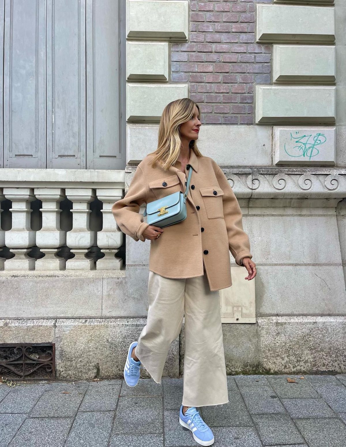 Neutral outfit with cream culottes, a shacket and light blue sneakers and Celine Triomphe bag.