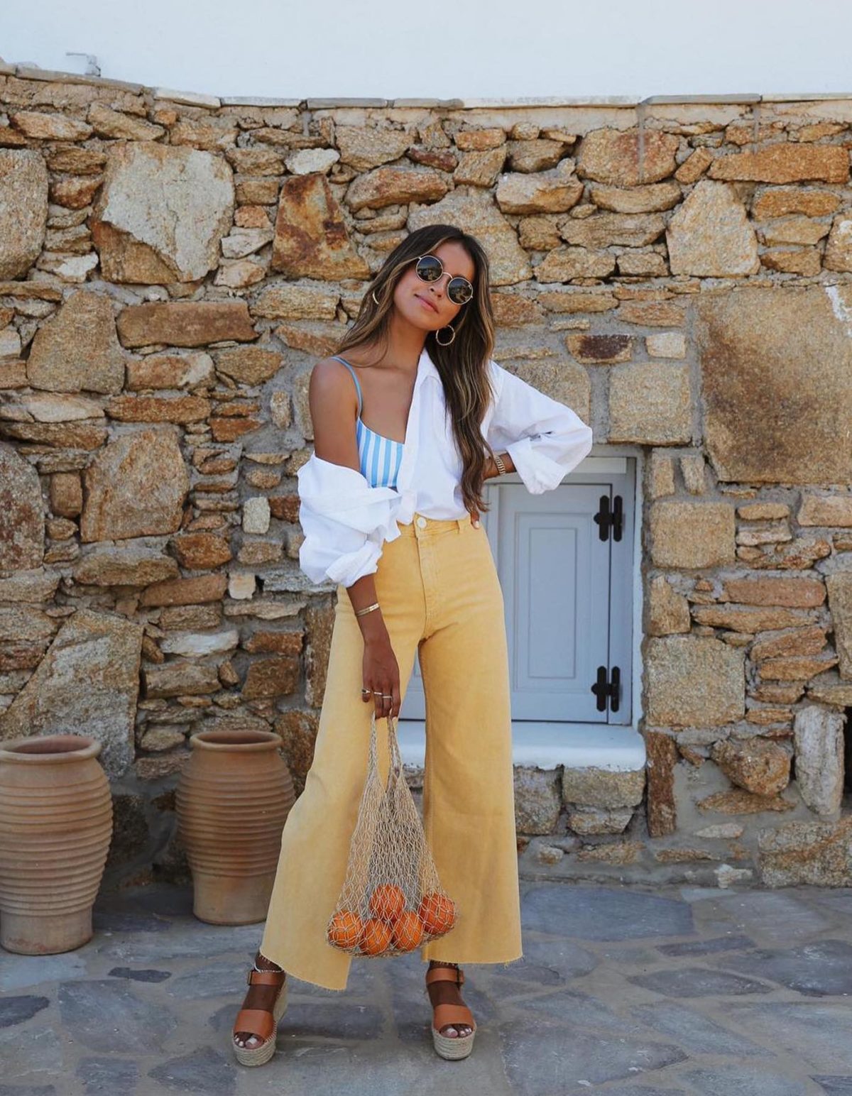 Colorful summer outfit with yellow culottes, orange wedges and a white button-up shirt.