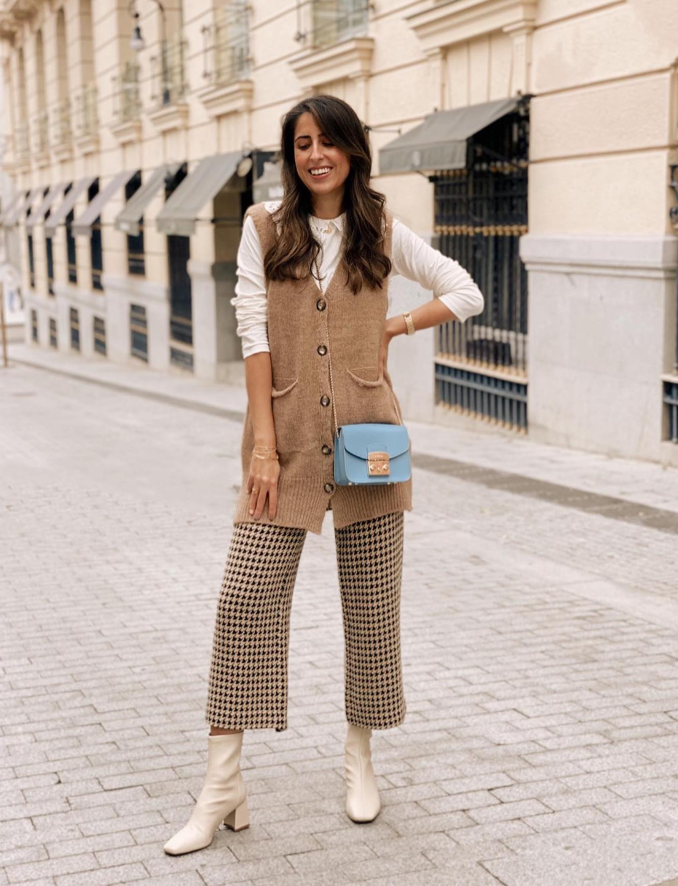 Neutral outfit with a beige sweater vest, gingham culottes and cream ankle boots.