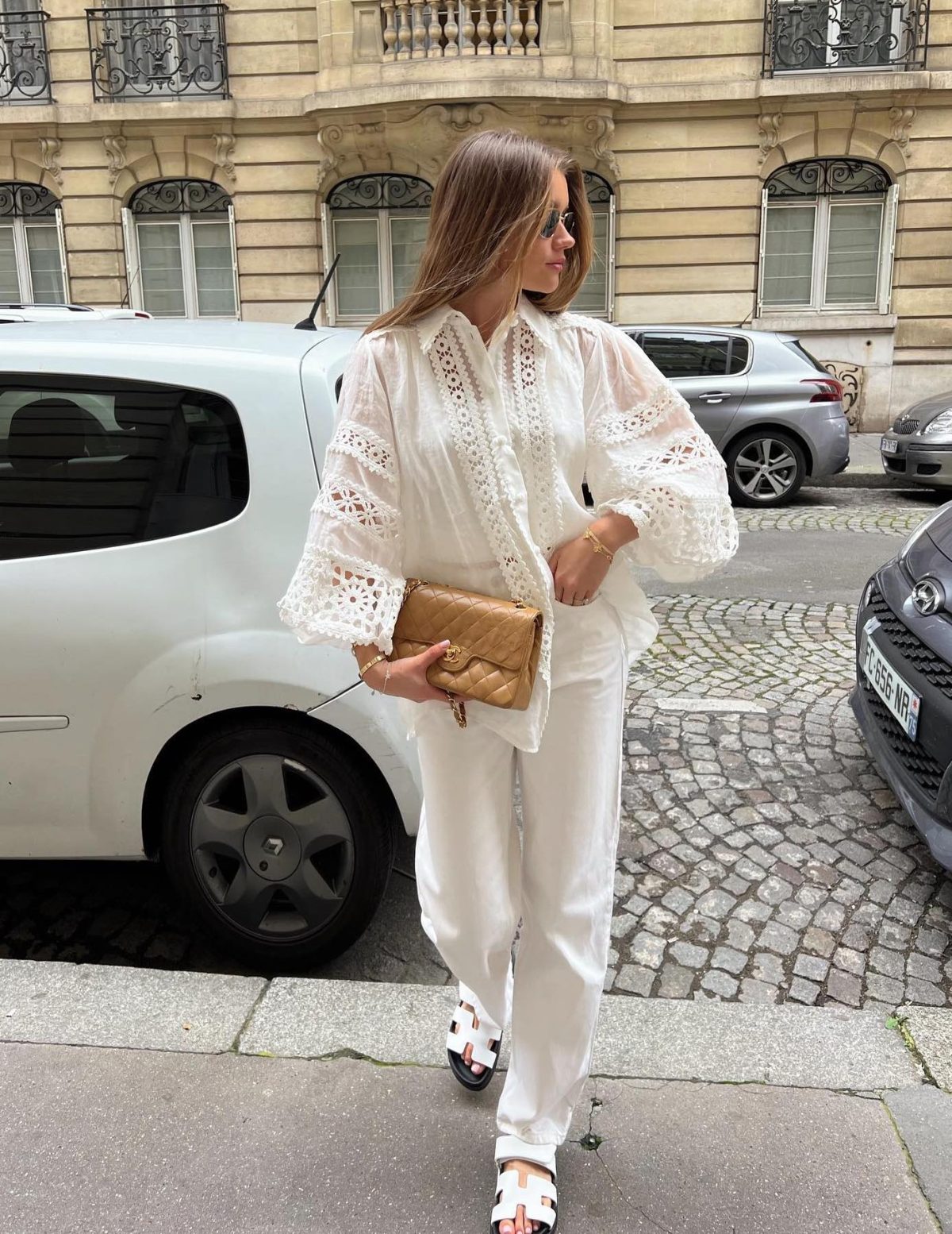 All white outfit with jeans, Hermes Chypre sandals, a blouse and beige Chanel bag.